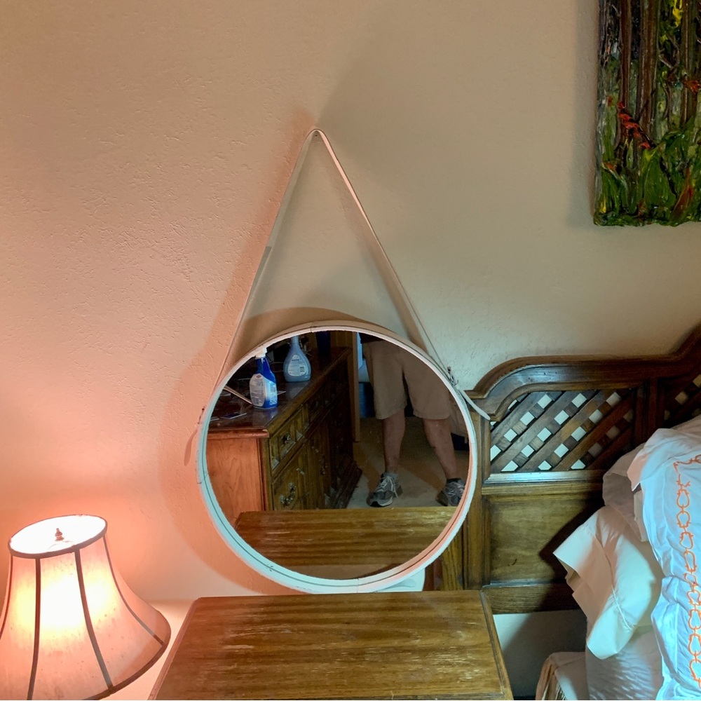 White leather cowhide mirror with non-adjustable strap hangs from a brass knob.